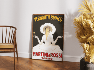 Vintage plakat med elegant kvinde i hvid kjole og hat, reklame for Vermouth Bianco fra Martini & Rossi, sort baggrund og rød tekst.

