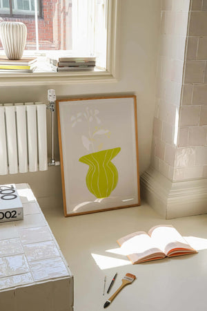 Plakat med grøn organisk form og fine linjer på lys baggrund i moderne indretning