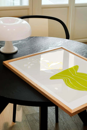 Plakat med grøn organisk form og fine linjer på lys baggrund i moderne indretning