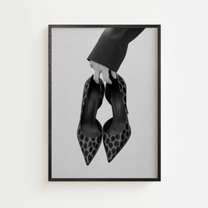 Sort hvid plakat med elegante stiletter holdt i hånden