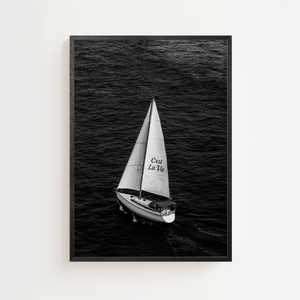 Sort-hvid plakat med sejlbåd på åbent hav og teksten C'est La Vie på sejlet.