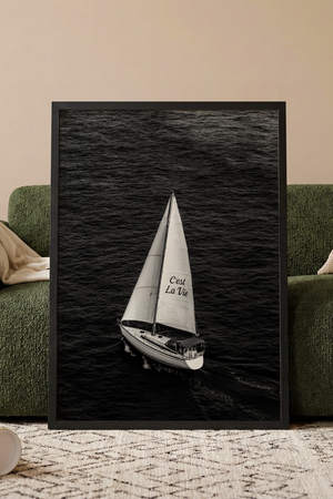 Sort-hvid plakat med sejlbåd på åbent hav og teksten C'est La Vie på sejlet.