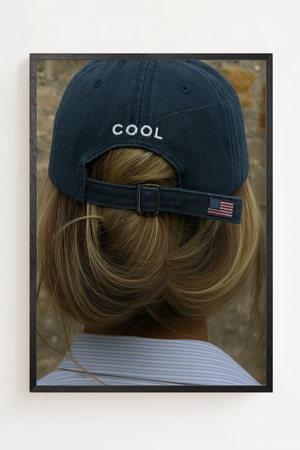 Modeplakat med person set bagfra iført mørk baseball cap med teksten COOL.