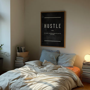 Hustle plakat med sort baggrund og hvid typografi og definition i egetræsramme over seng