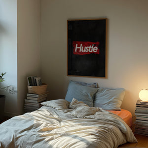 Hustle plakat med hvid slidt typografi på mørkerød tekstureret baggrund i egetræsramme over seng