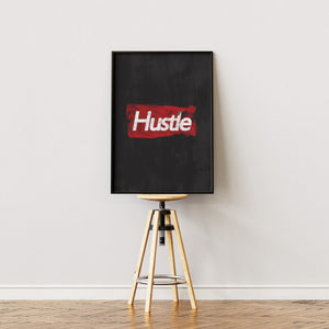 Hustle plakat med hvid slidt typografi på mørkerød tekstureret baggrund i egetræsramme på staffeli