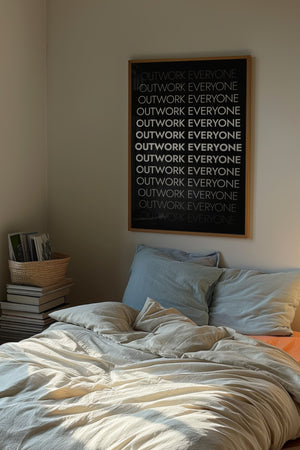 Outwork Everyone plakat med gentaget hvid tekst i varierende tykkelser på sort baggrund i egetræsramme over seng