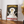 Vintage plakat med elegant kvinde i hvid kjole og hat, reklame for Vermouth Bianco fra Martini & Rossi, sort baggrund og rød tekst.

